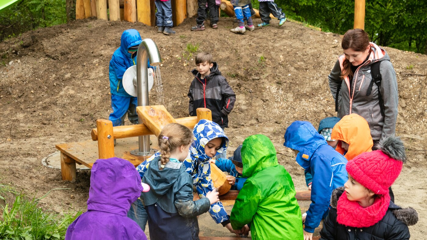 Kinder auf Spielplatz mit Wasserleitung