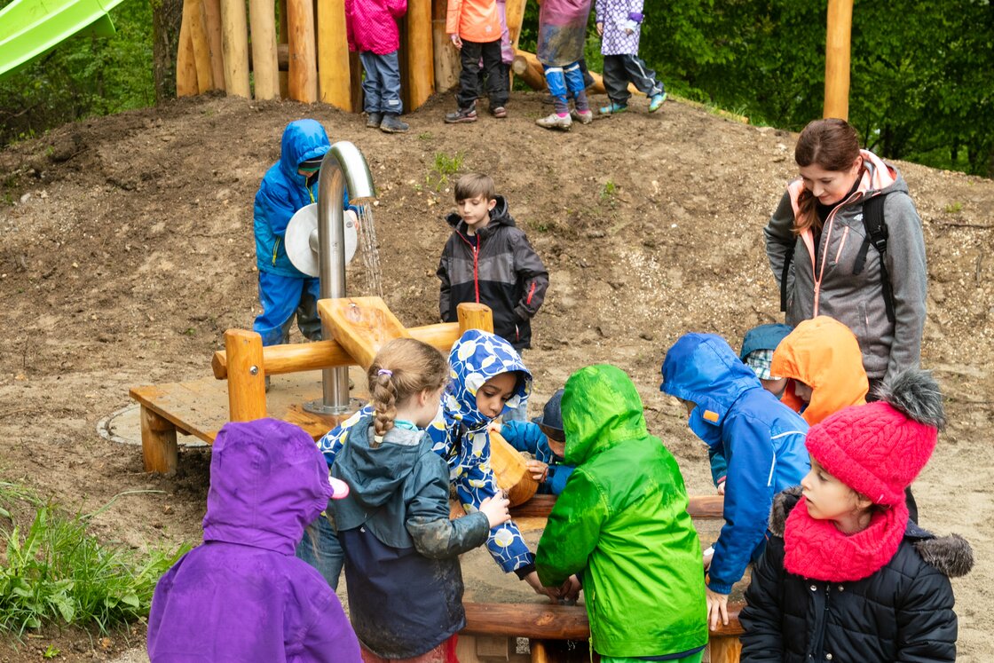 Kinder auf Spielplatz mit Wasserleitung