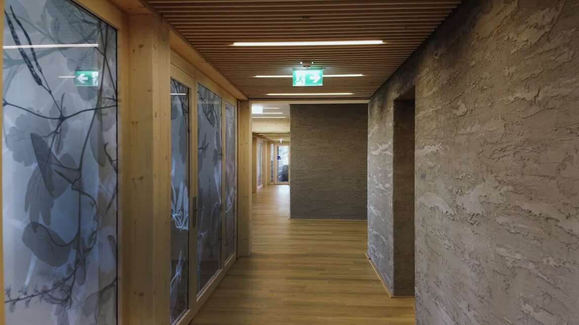 Interior view of EGK headquarters with clay plaster and door glazing with a floral pattern.