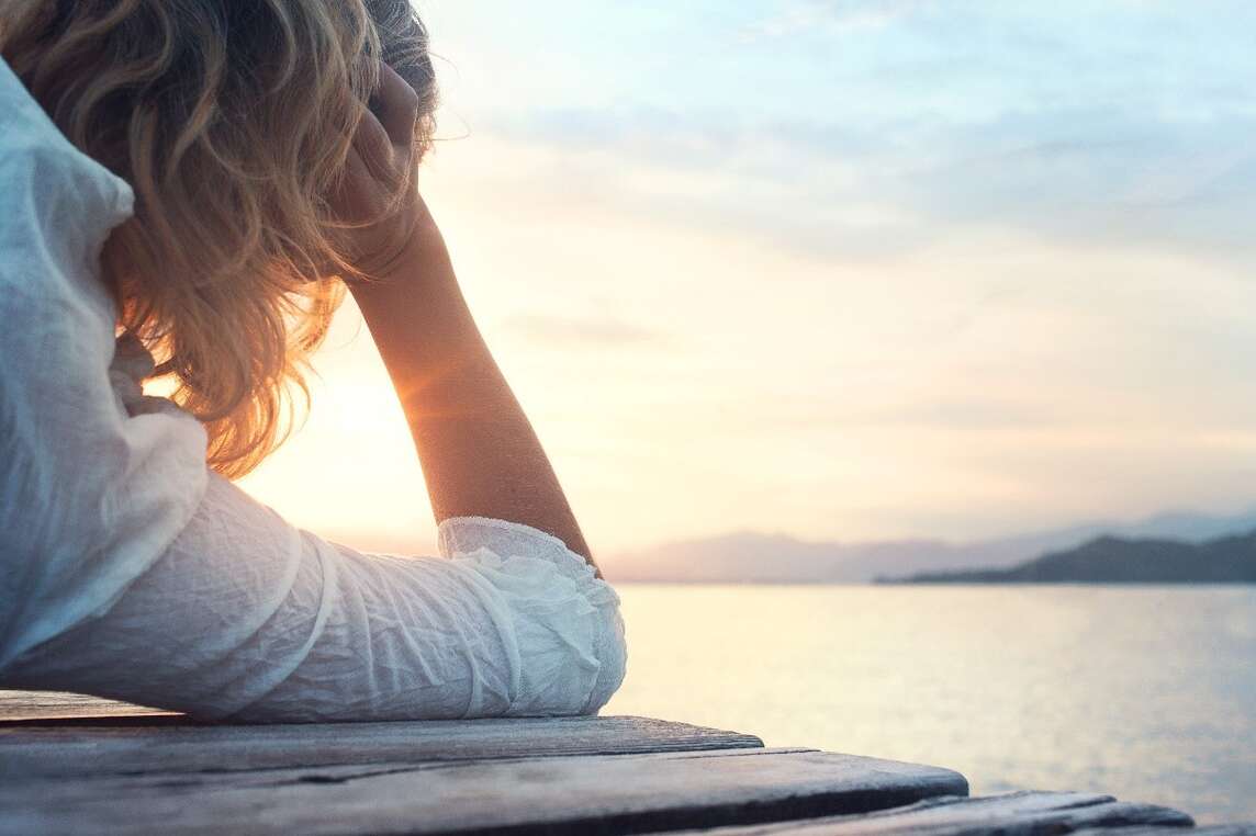 Nahaufnahme Frau von hinten liegend auf Steg am See.